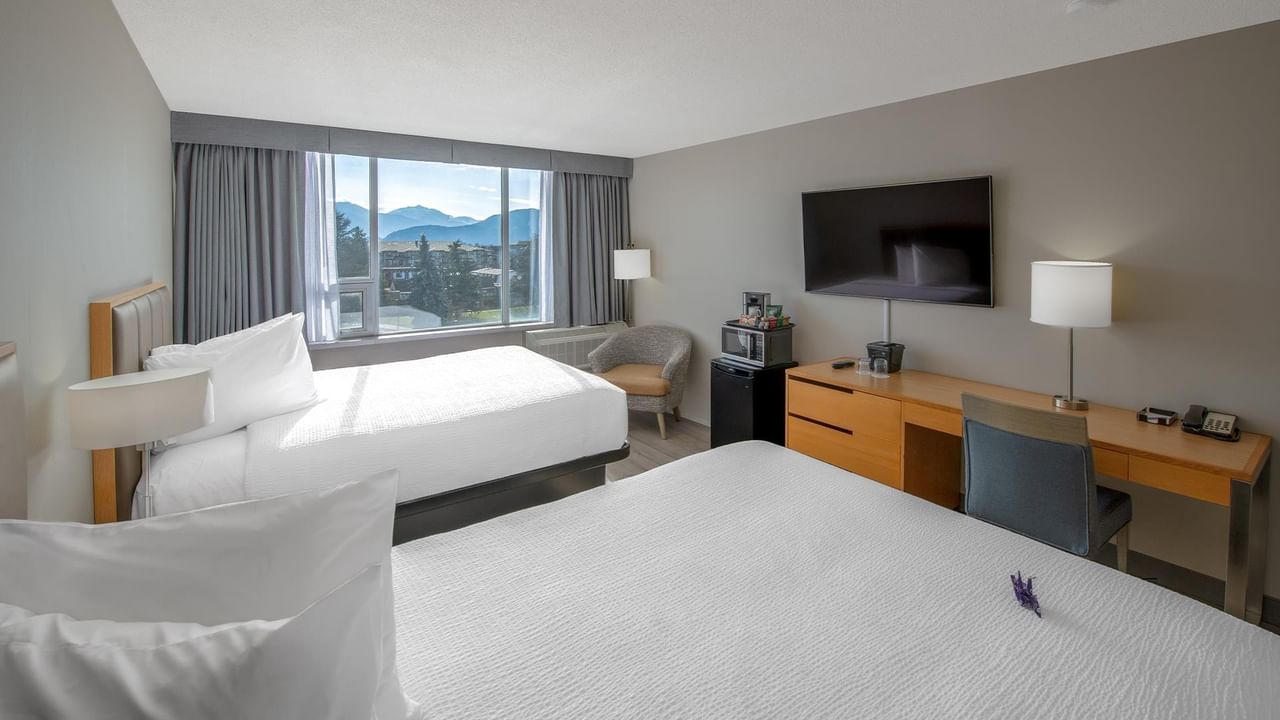 Two beds, desk, and chair in a hotel room.