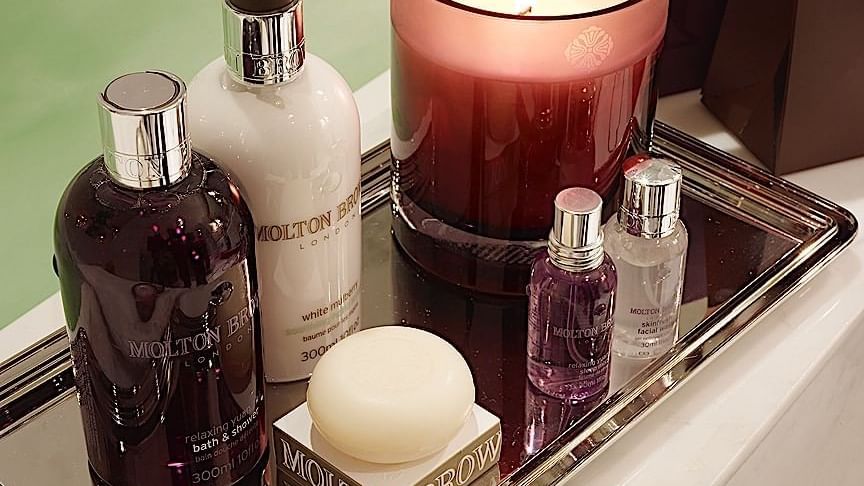 Molton Brown toiletries with a lit candle arranged neatly on a tray in Grand Deluxe Suite at El Prado Hotel