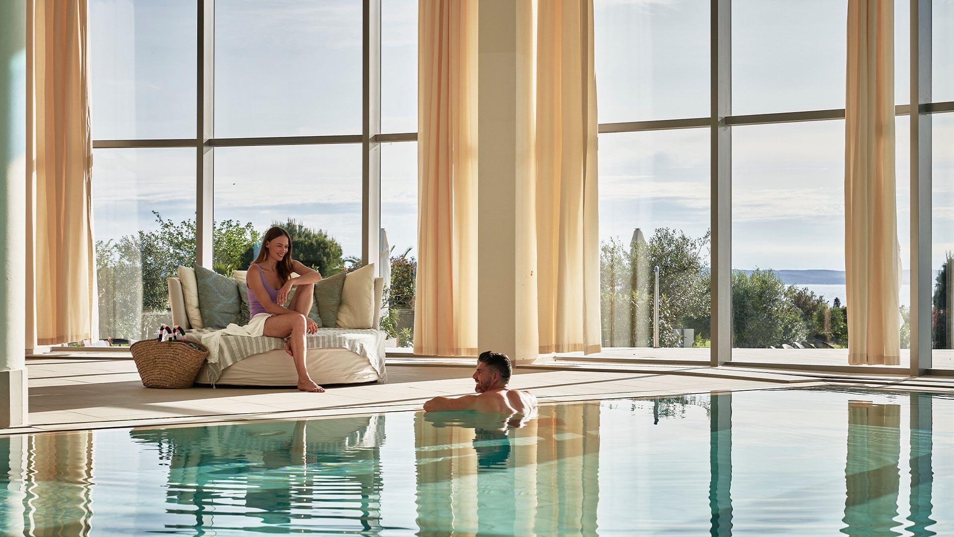 Couple relaxing by the indoor pool at Falkensteiner Hotels & Residences