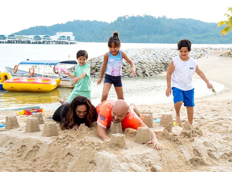 A family playing with sand castles on the beach -Lexis Hibiscus