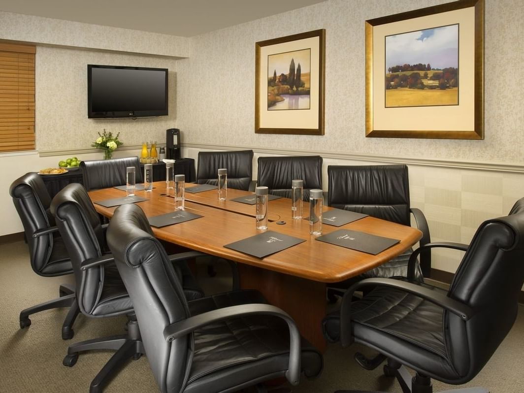 Meeting table set with pads, water bottles, and a food station in the Snoqualmie Boardroom at Redmond Inn