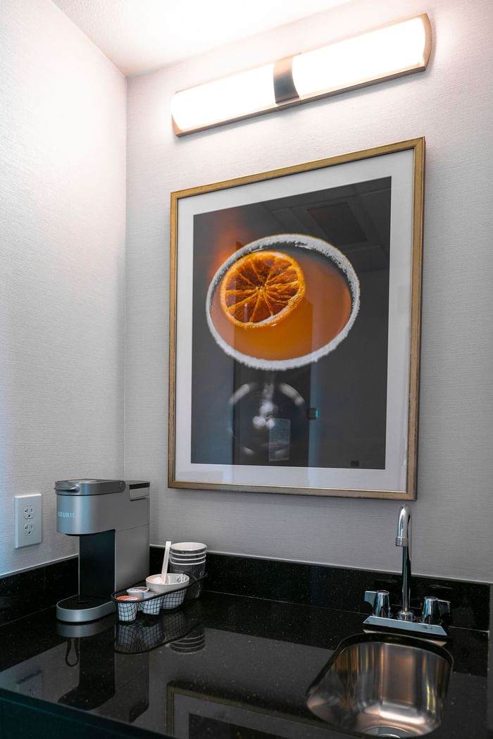A kitchen with a sink, coffee maker and wall art in Hotel 43