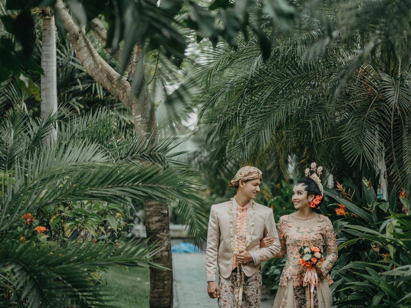 Newly wedded couple walking in a path surrounded by trees in Traditional Malay outfits at Saujana Hotel Kuala Lumpur