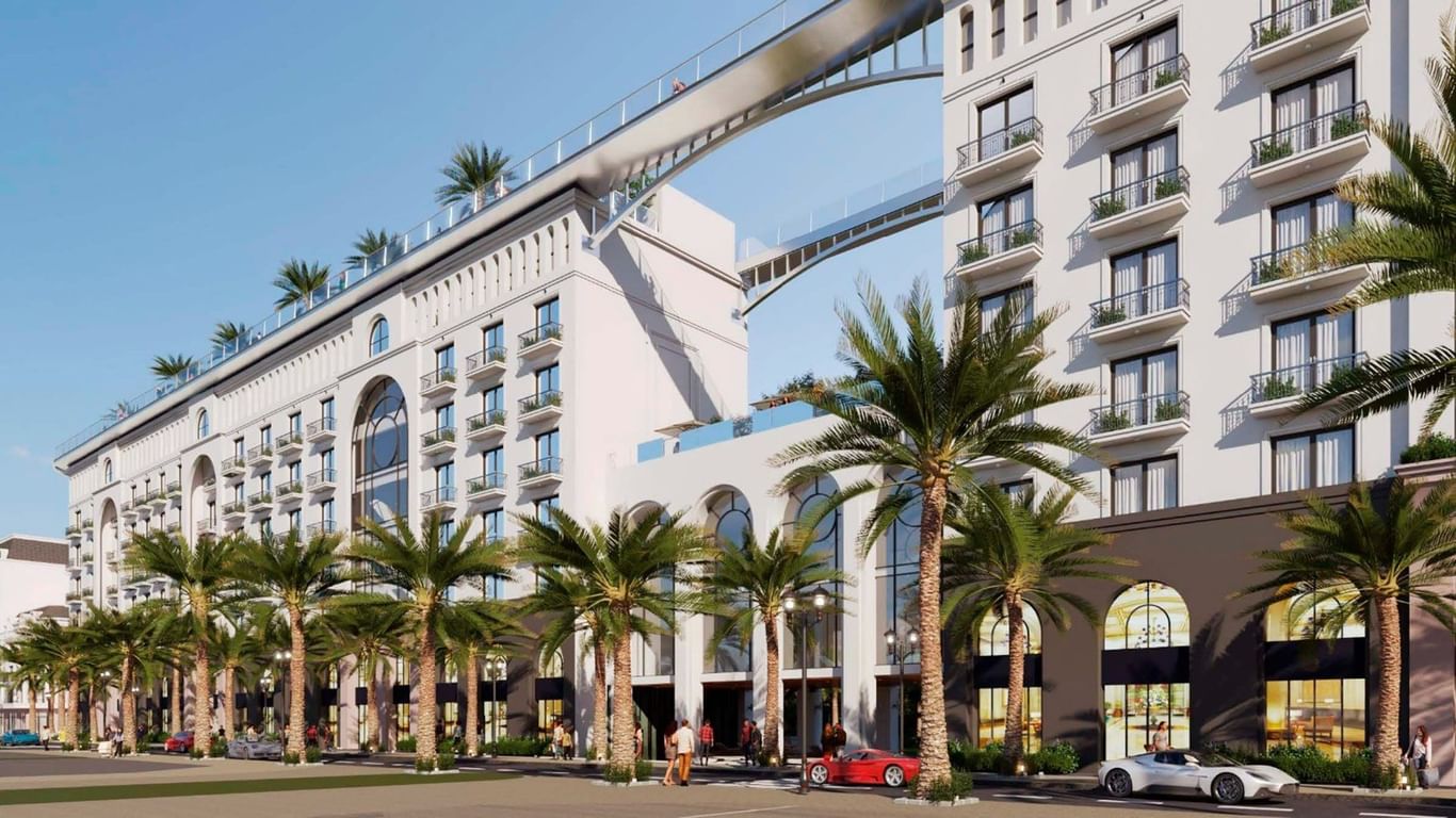 Modern white hotel building with palm trees lining the entrance and multiple balconies at Warwick Corporate