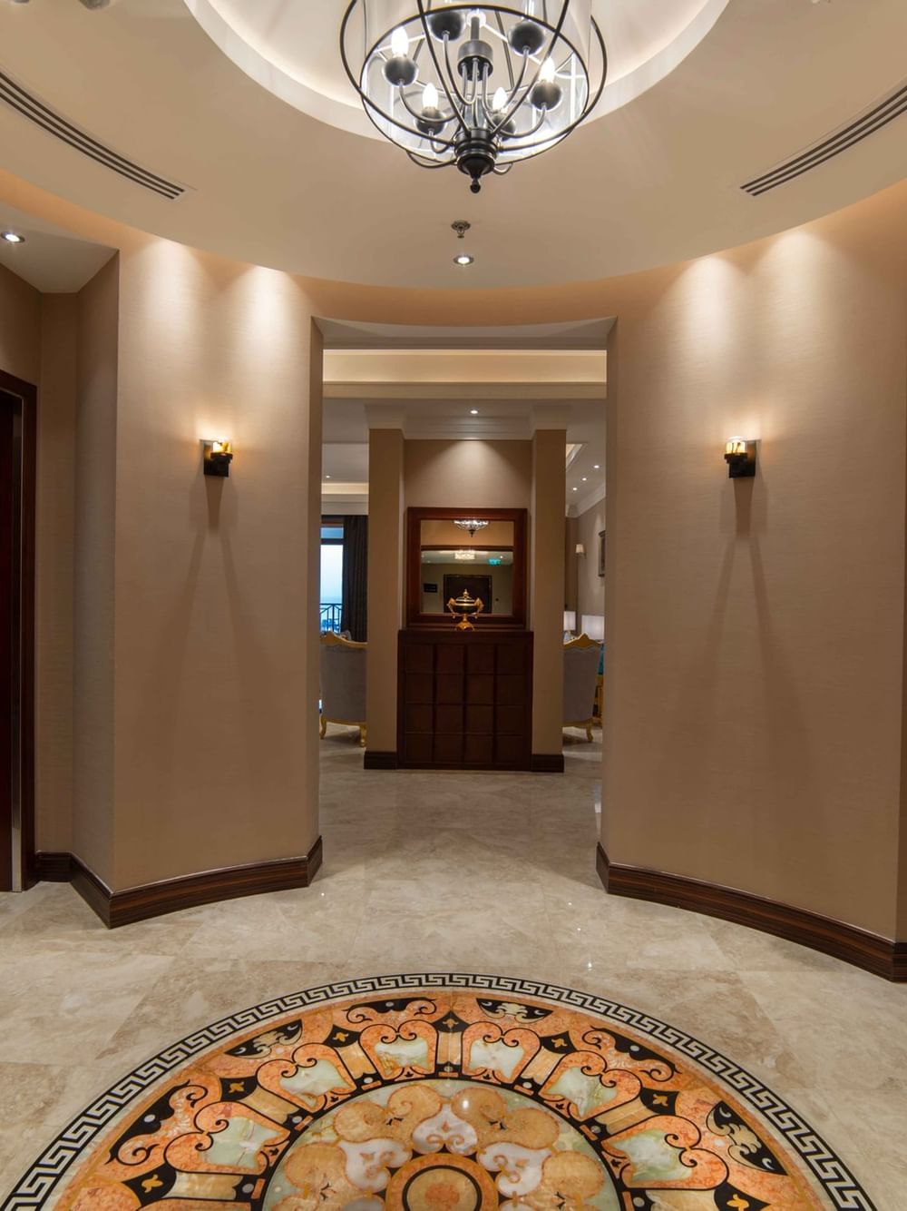 Ornate marble floor medallion by arched corridors under a modern cage chandelier in Penthouse Villa at Warwick Al Khobar