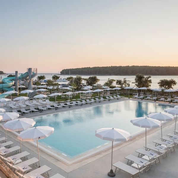 Aerial view of outdoor pool surrounded by sunbeds at Falkensteiner Hotels & Residences