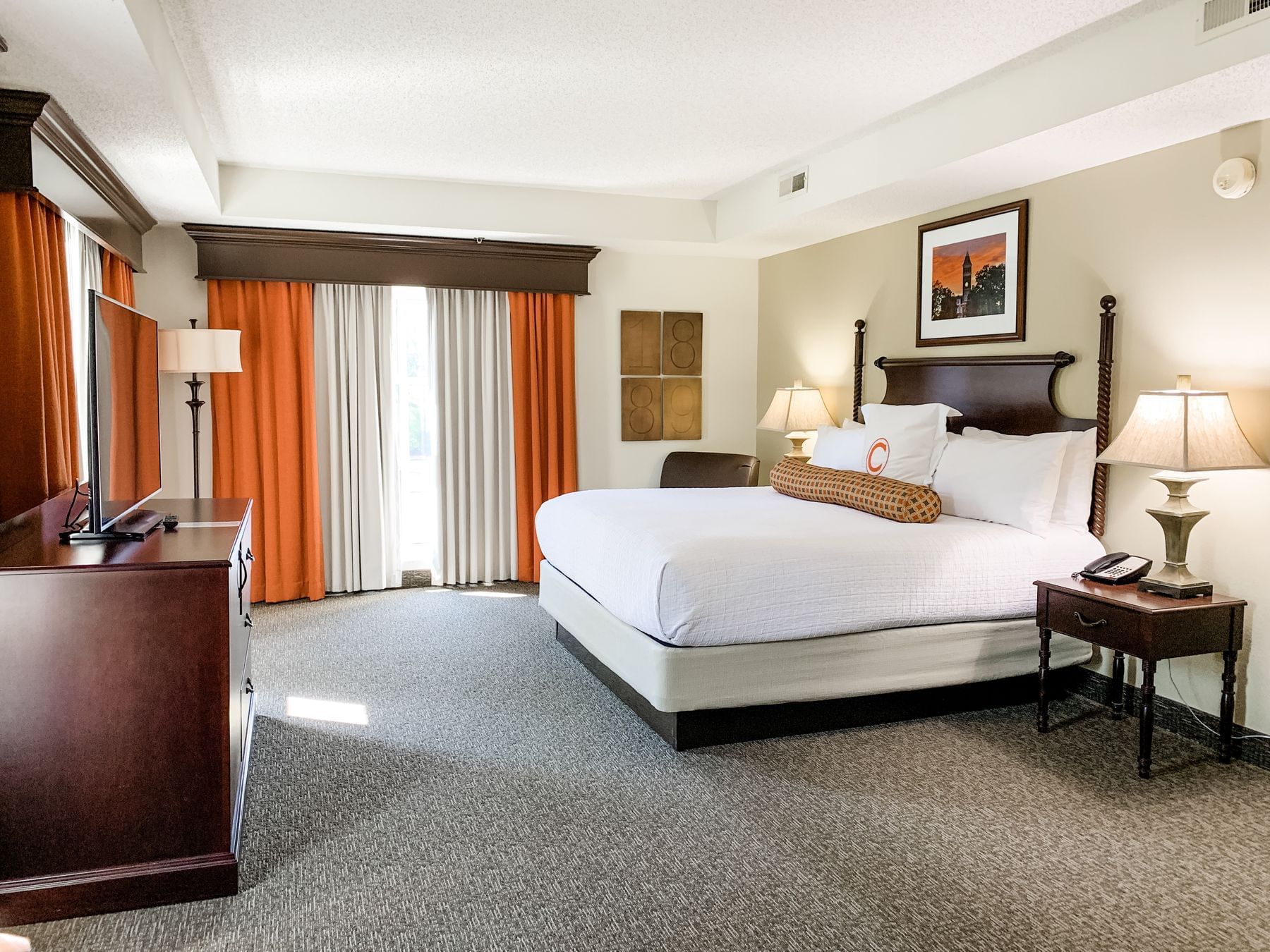 spacious room with bed and window with orange curtains