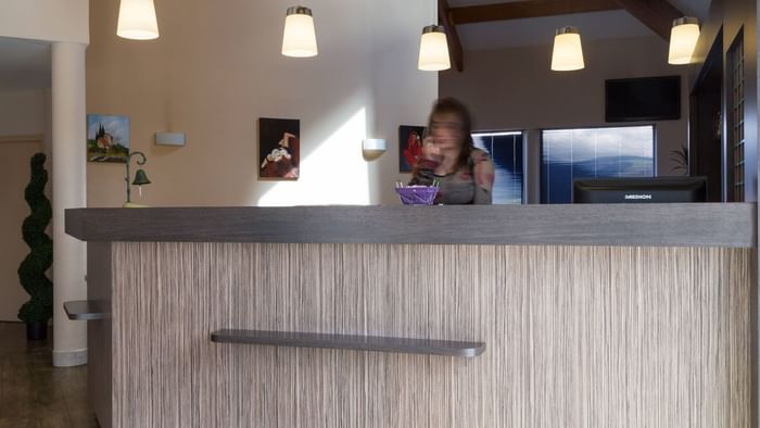 A receptionist at the reception desk in Hotel L'Acropole