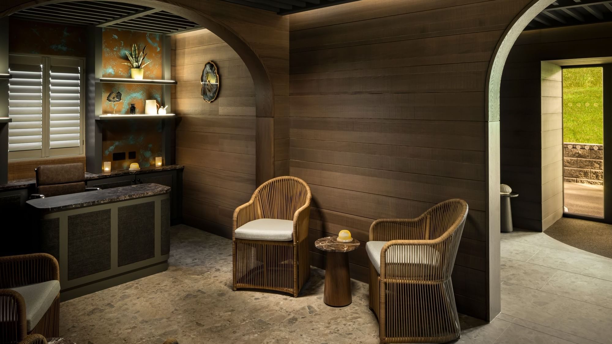 Spa lounge area with two wicker chairs, a small table, and a desk under a curved wooden ceiling at Dunluce Lodge