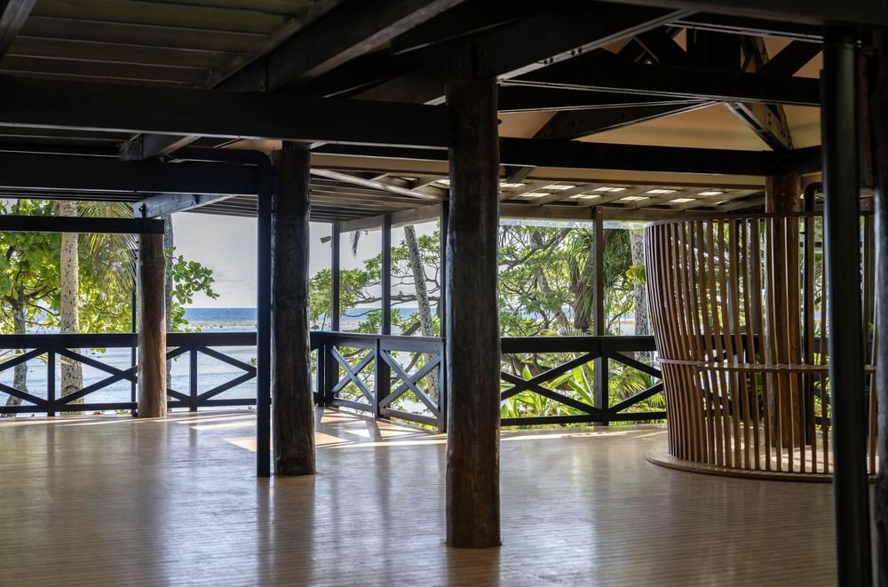 Wooden deck with thick pillars by a black railing under a beamed roof at Warwick Fiji Resort and Spa