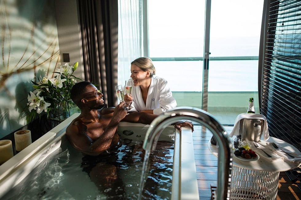 Couple relaxing in a bathtub with seaside view in room at Live Aqua Resorts and Residence Club