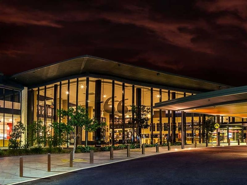 Illuminated Panthers Penrith Rugby Leagues Club at night with dark sky and driveway in front.