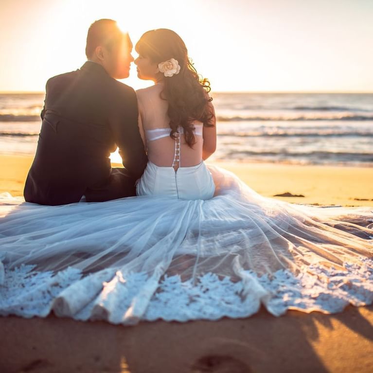 bride and groom sitting on sand