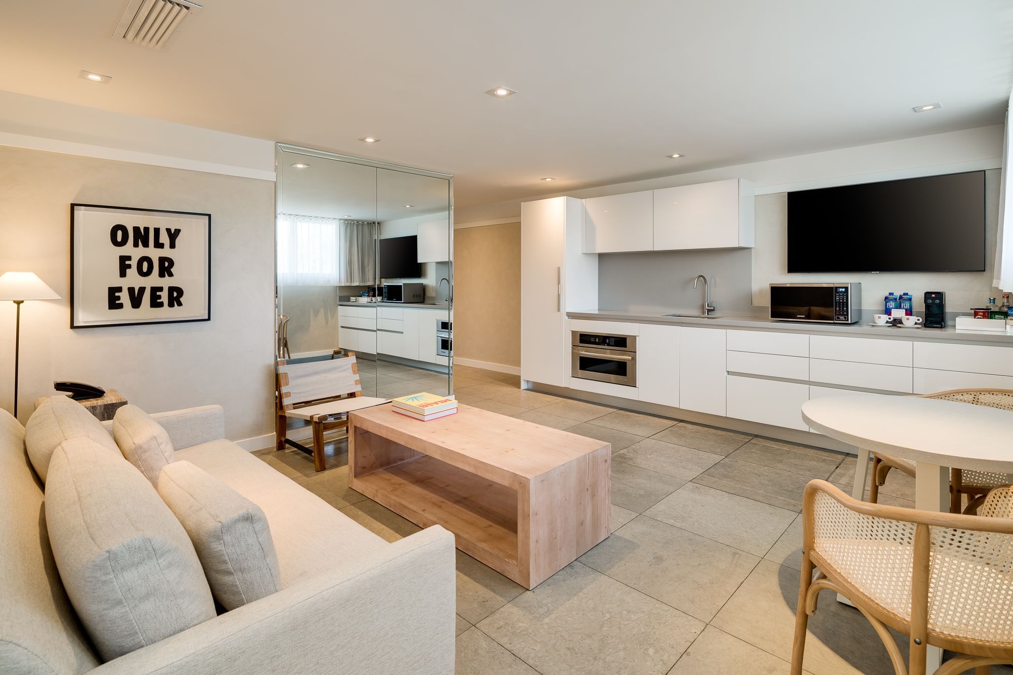 A wide view of a suite's living area with kitchenette, dining table, and sofa.