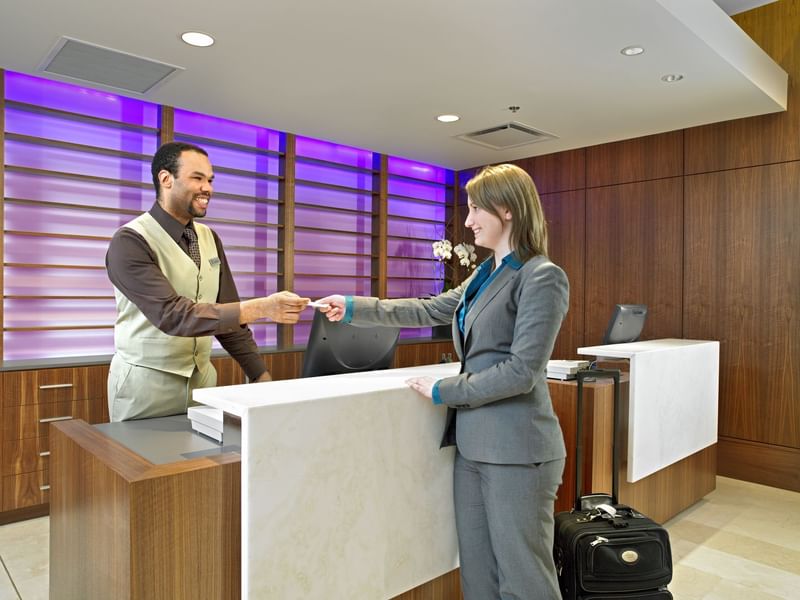 Hotel clerk checking in happy guest