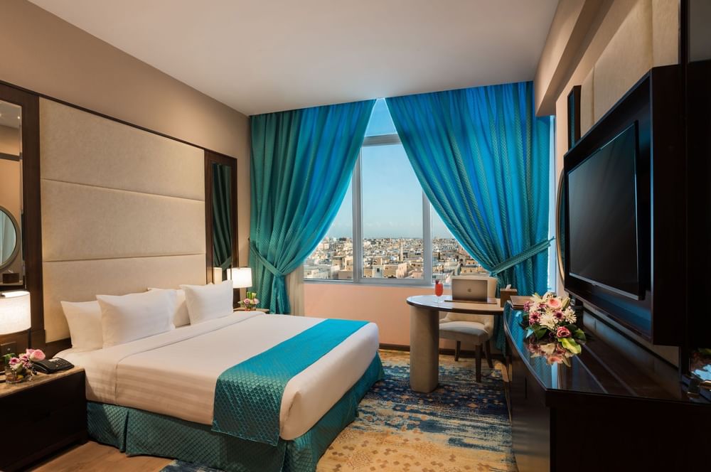 TV facing bed with a work desk near the window in Junior Suite at Naviti By Warwick Dammam