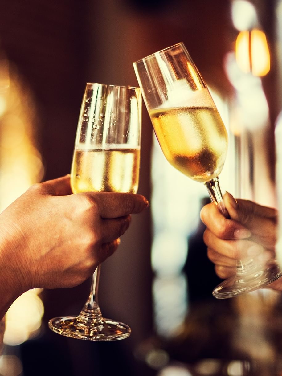Deux personnes trinquent avec des flûtes de champagne dans une ambiance festive et chaleureuse