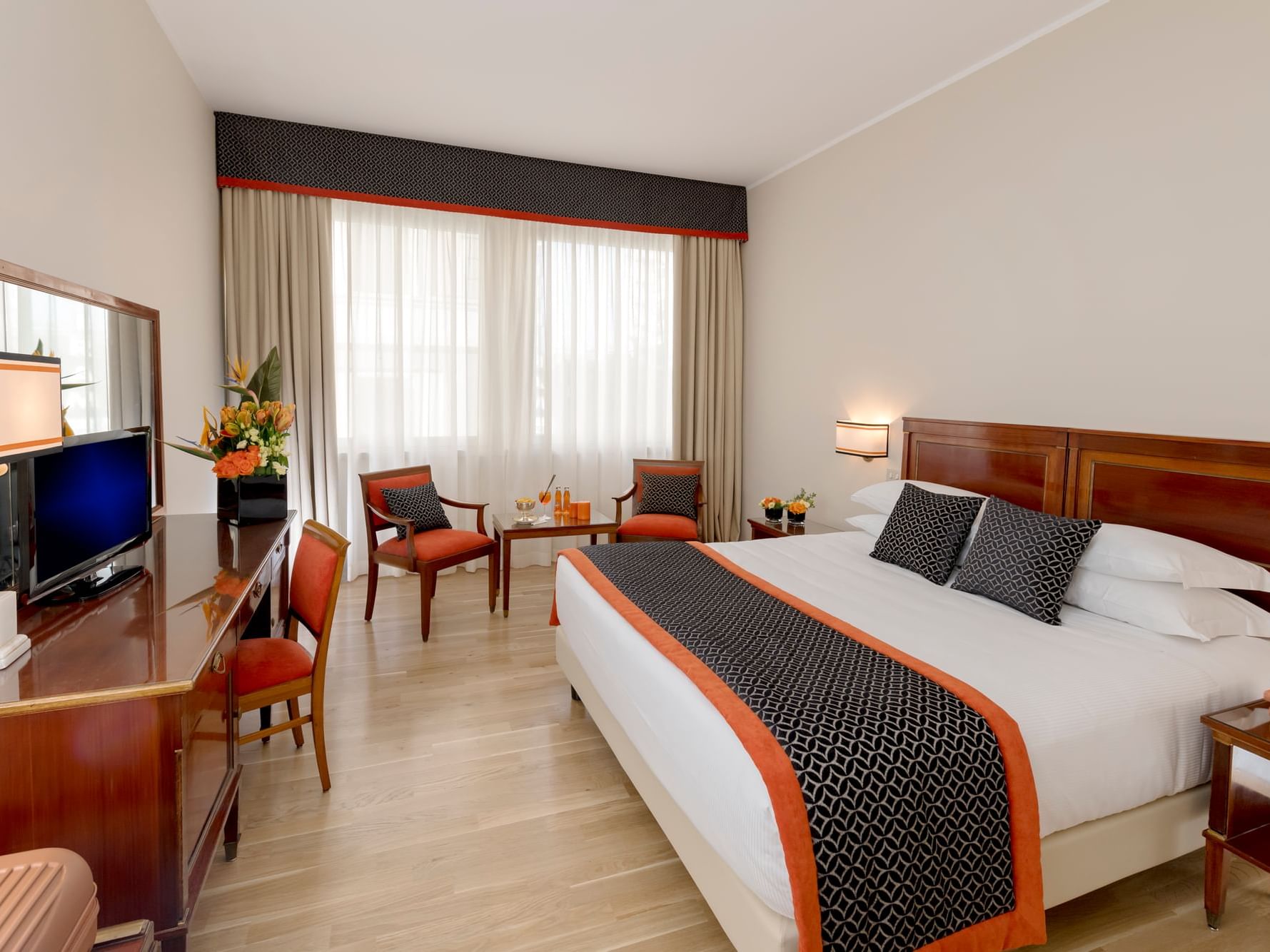 Large bed, chairs with coffee table, work desk & TV in Deco Family & Friends Room at Bettoja Hotel Mediterraneo