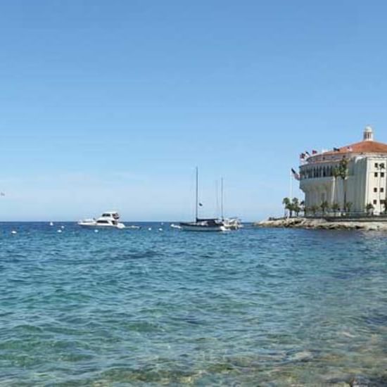 Seaside view with boats and a building on the right under a clear sky at Banning House Lodge