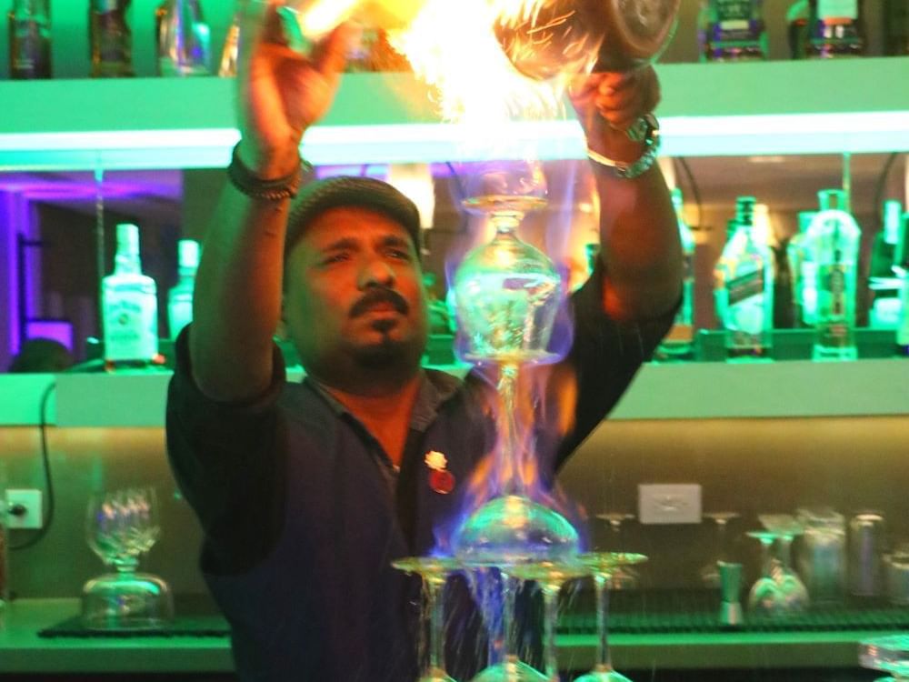 A bartender pouring a drink into a glass at Alaia Belize Autograph Collection