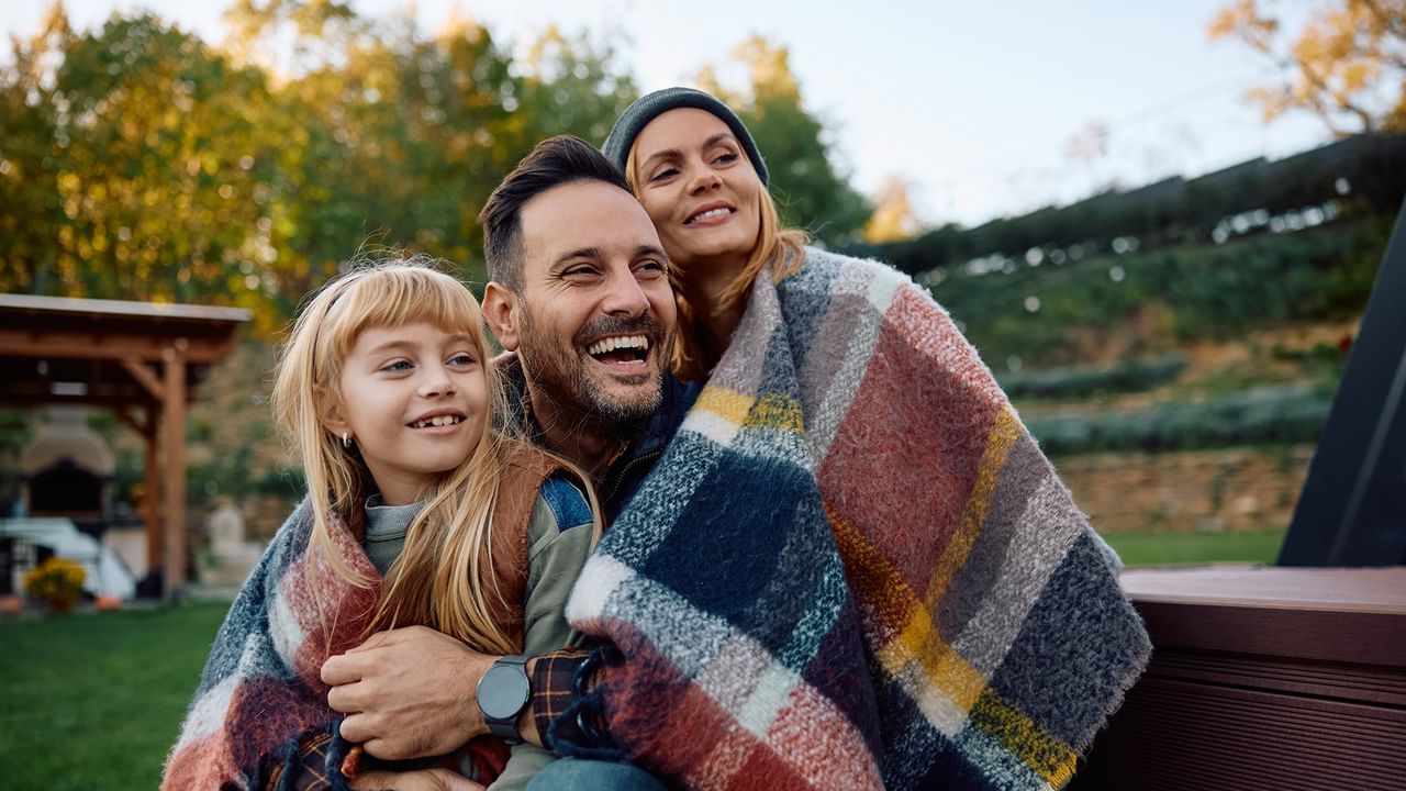 A family of three wrapped in plaid blankets smiling