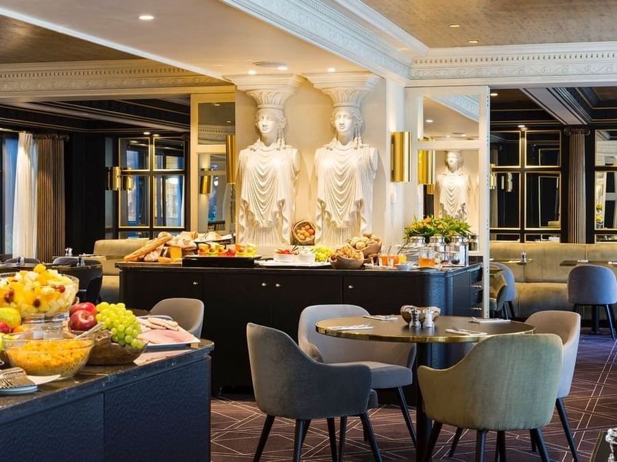 Breakfast buffet featuring bowls of fruit with Greek Caryatid statues in The Avenue Restaurant at Hotel Barsey by Warwick 