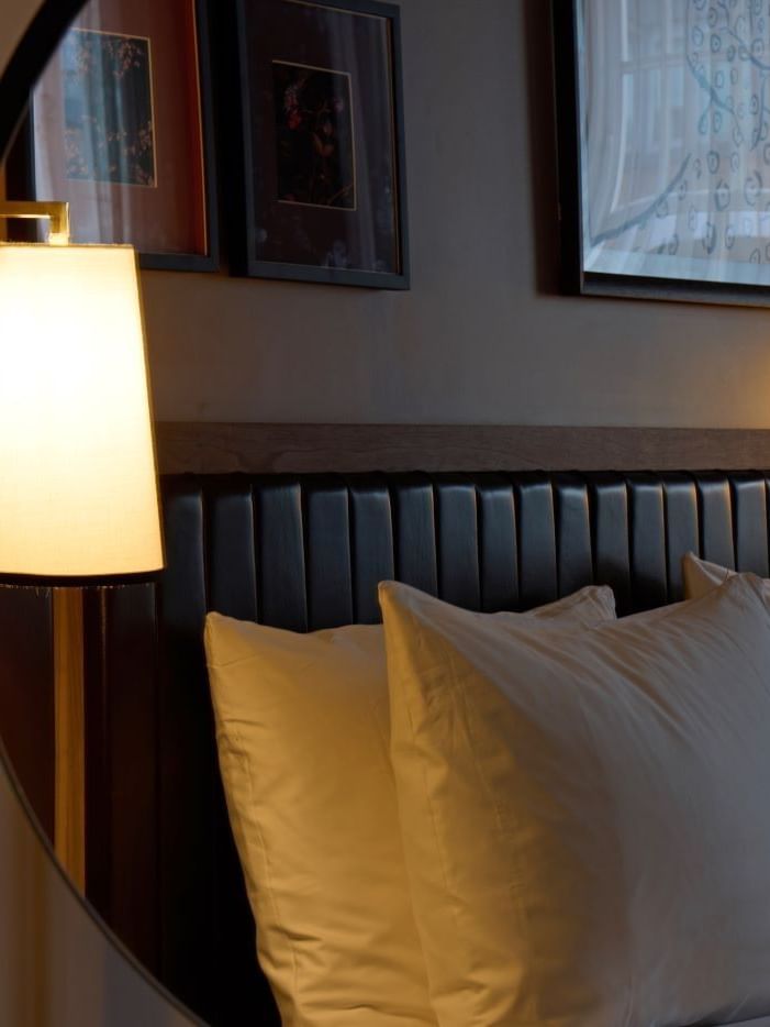 A cozy bed with white pillows and a lit lamp, reflection of a Collection Superior Bedroom in the mirror at The May Fair Hotel, London..