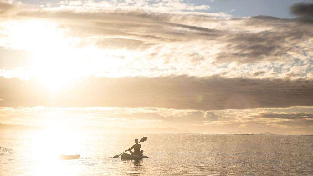 Silhouette of a kayaker enjoying the sunset on water at Warwick Fiji Resort and Spa in Korolevu.