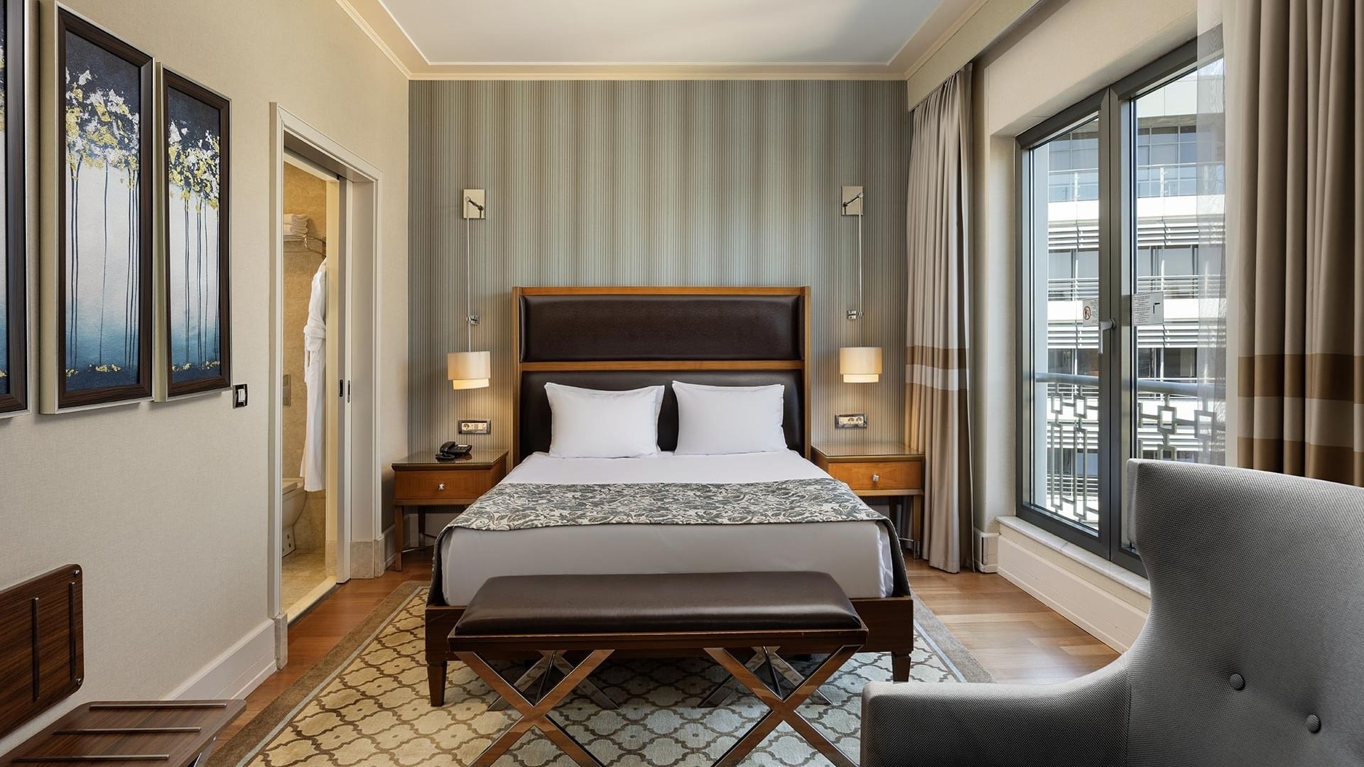 Titanic City Taksim'deki deluxe oda, çift kişilik yatak, iki lamba, büyük pencere ve modern mobilyalarla dekore edilmiştir.