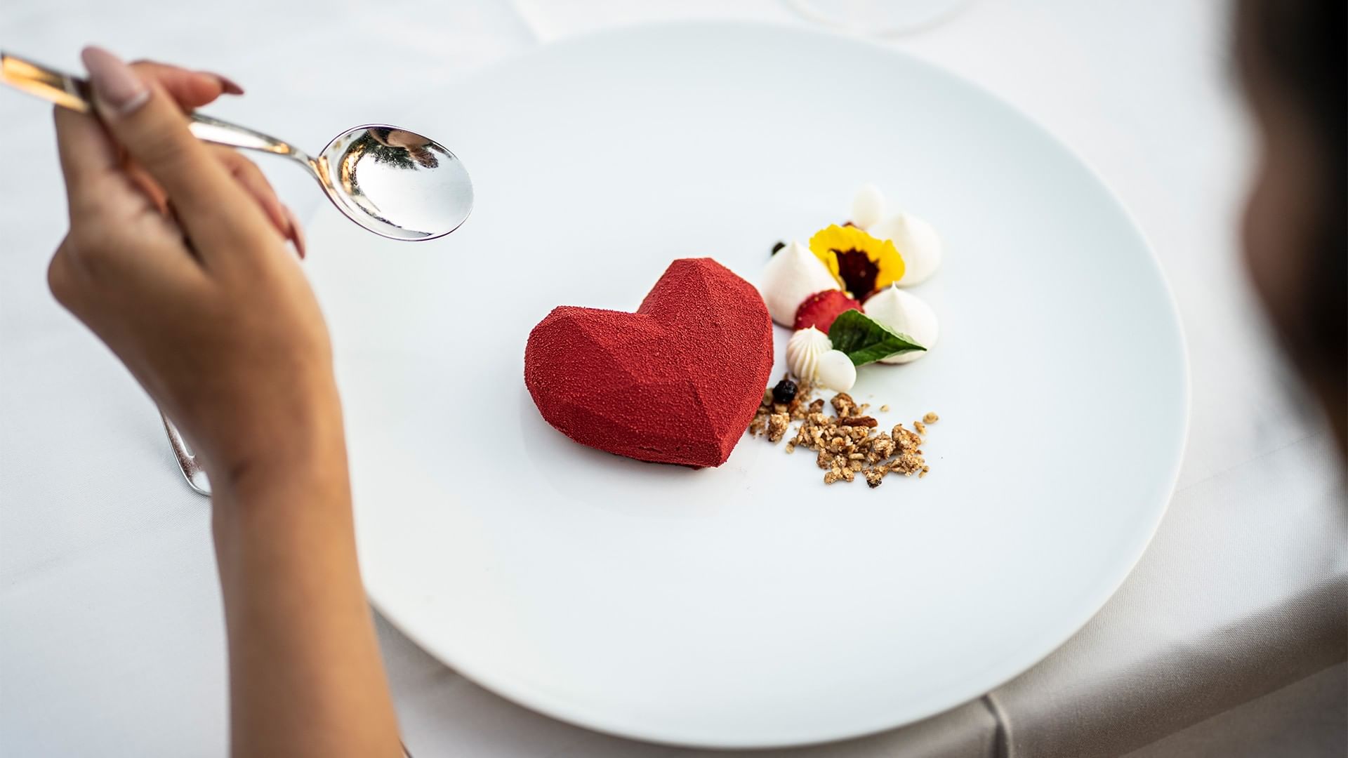 Person eating a red heart shaped dessert with a spoon at Falkensteiner Club Funimation Borik