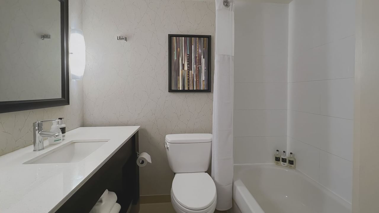 Bathroom with towels, toilet, mirror, shower and sink