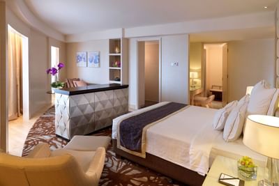 Room featuring a king bed, functional desk & comfy chair in Executive Suite with carpeted floors at One World Hotel