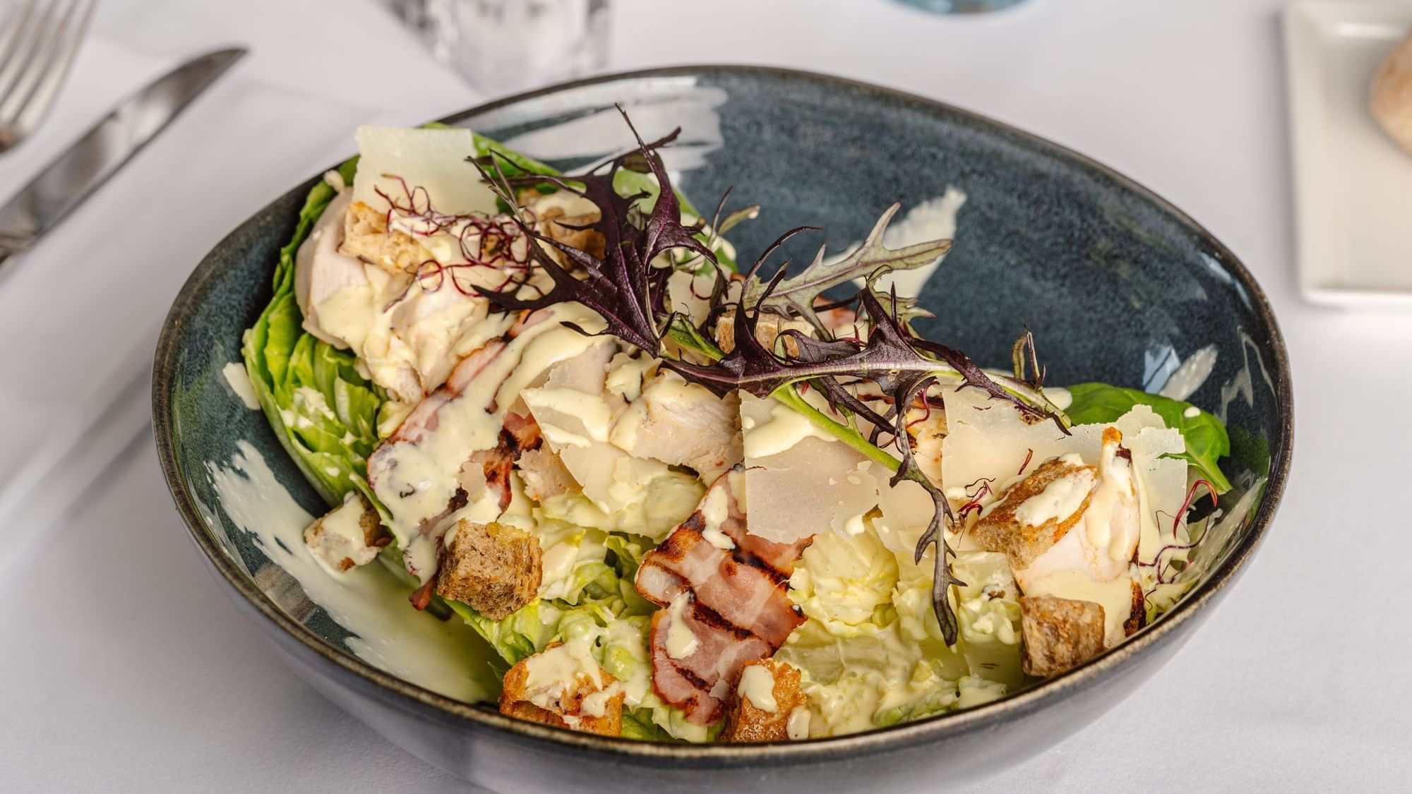 Caesar salad with grilled chicken and bacon chips served in Teseo Restaurant at Warwick Geneva