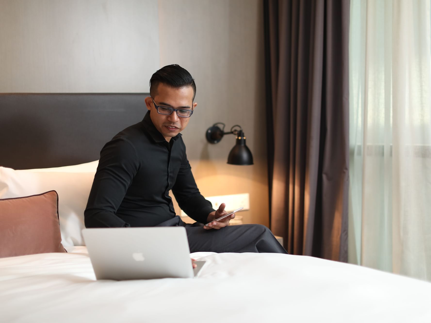 Man using a laptop on bed in a room at VE Hotel & Residence