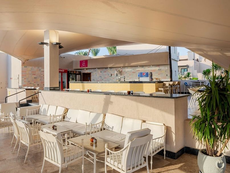 بار المسبح بأثاثه الأبيض وطاولته في فندق بيكالباتروس ساندز بورت غالب.