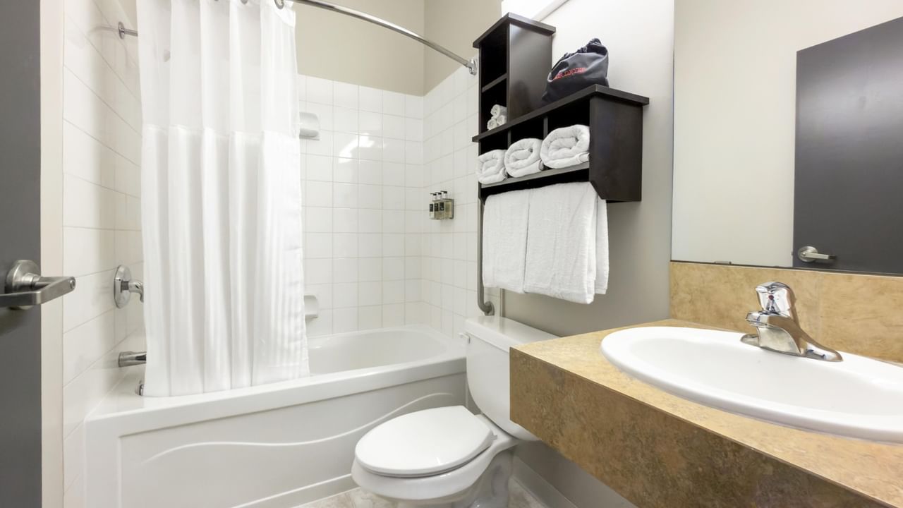 Guest bathroom at Coast Innisfail Hotel with bathtub, toilet and vanity