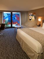 Classic Room features King bed by a curved desk and sofa under a framed art piece at Warwick Seattle