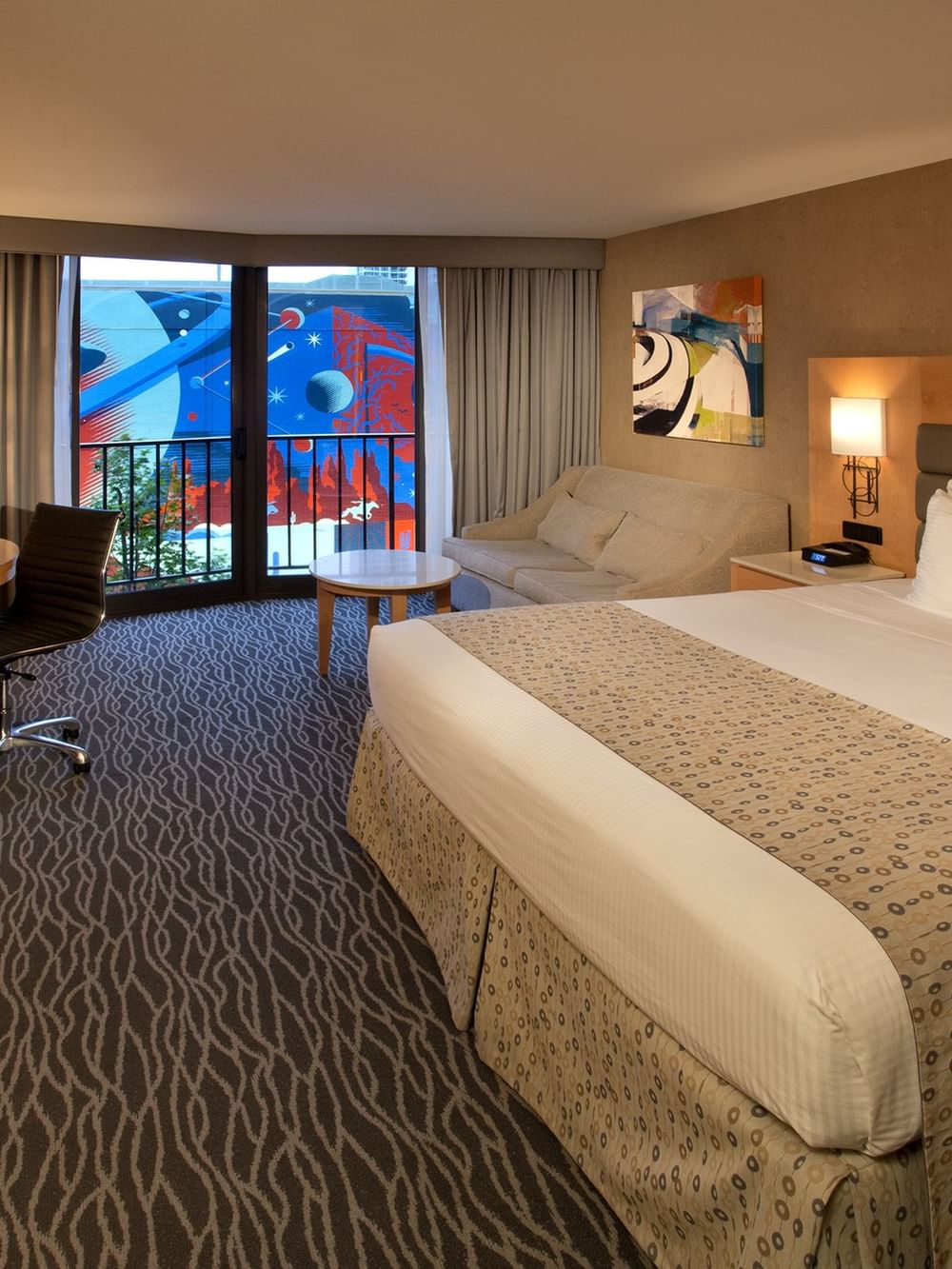 Classic Room features King bed by a curved desk and sofa under a framed art piece at Warwick Seattle