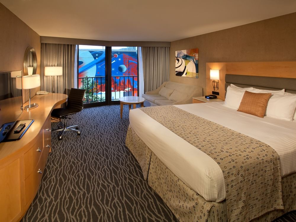 Classic Room features King bed by a curved desk and sofa under a framed art piece at Warwick Seattle
