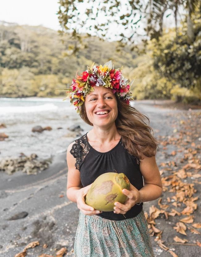 A lady holding a coconut on a beach with a floral headpiece near Ladera Resort, Saint Lucia