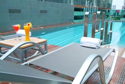 Two juice glasses & Bath towels by the pool at Amora Neoluxe Hotel Bangkok