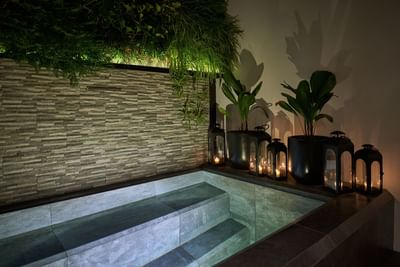 Luxurious outdoor jacuzzi, illuminated by candles and a green wall in Casa Cielo at Singular Signature Residences