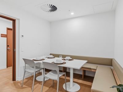 White dining area with table, chairs, and bench in UniLodge Brisbane City.