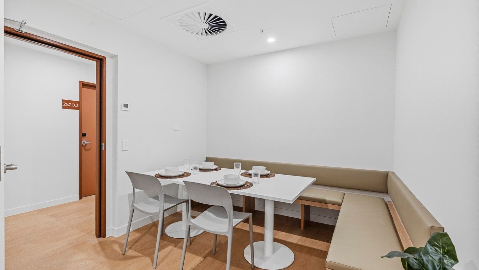 White dining area with table, chairs, and bench in UniLodge Brisbane City.