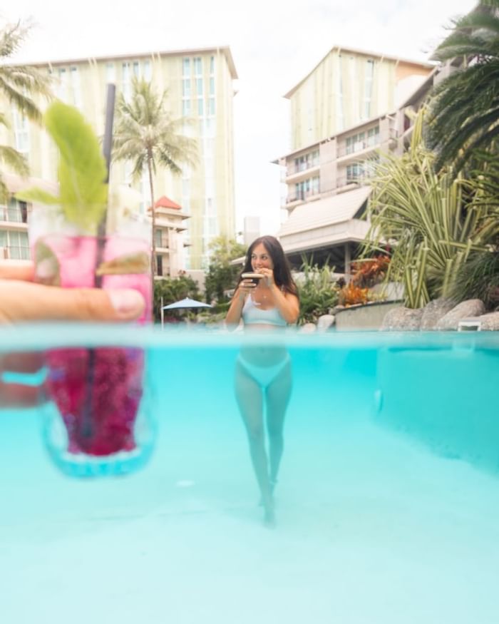 A lady at a pool with a beverage in Novotel Cairns Oasis