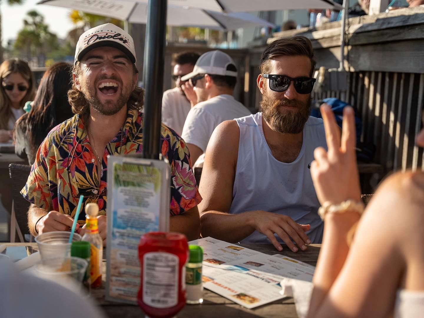 Two men sitting at a table with menus and drinks, laughing and having a good time.
