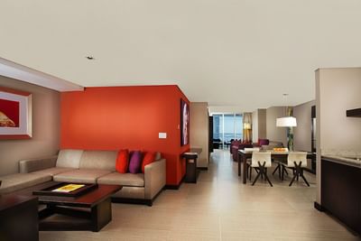 Sectional sofa & dark wood coffee table set by an orange accent wall in Studio Suite Ocean View at Megapolis Hotel Panama