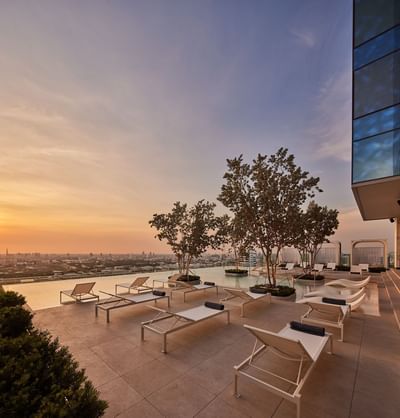 Outdoor swimming pool with sun loungers captured during sunset at Eastin Hotels