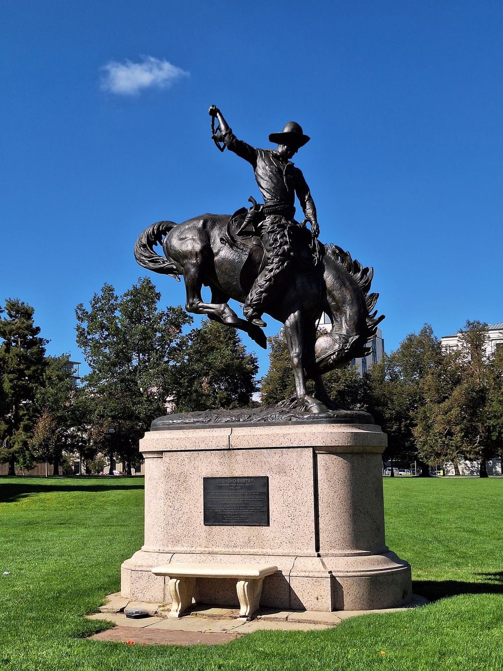 Statue Denver on a stone base surrounded by a lush green park at Warwick Denver