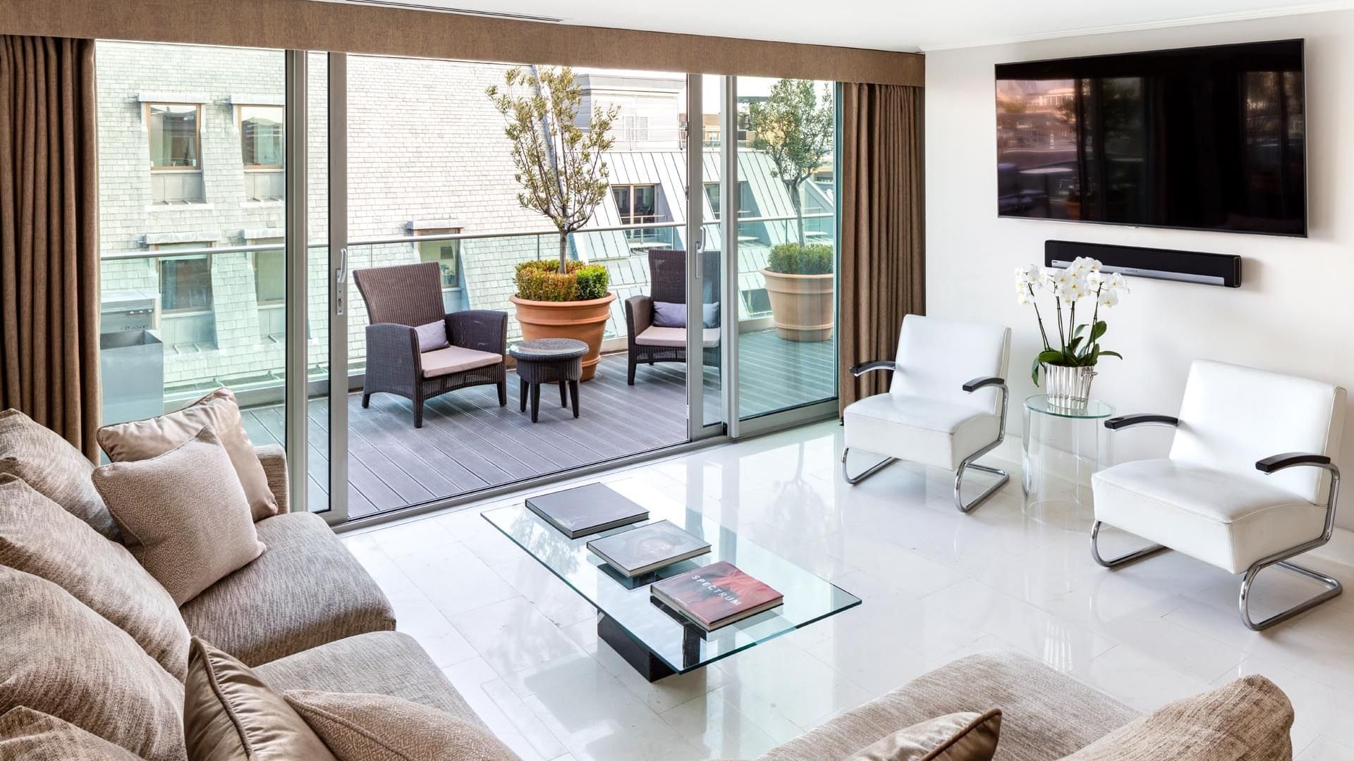 Modern Penthouse Suite living room at The May Fair Hotel, London, with sofas, white chairs, coffee table, and balcony access